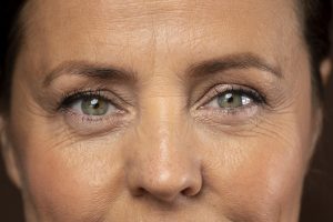Extreme close-up of a middle-aged woman with green eyes and visible hooded eyelids.