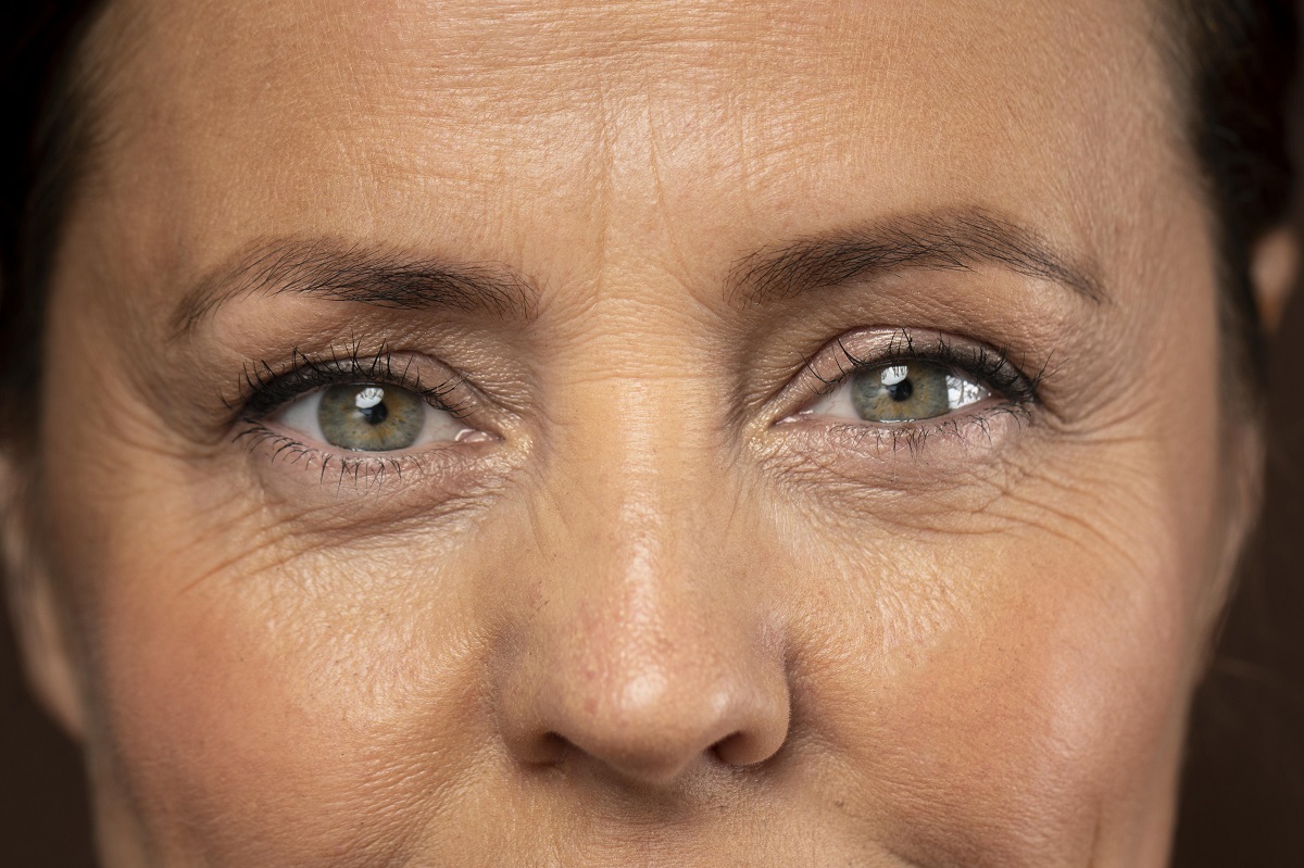 Extreme close-up of a middle-aged woman with green eyes and visible hooded eyelids.